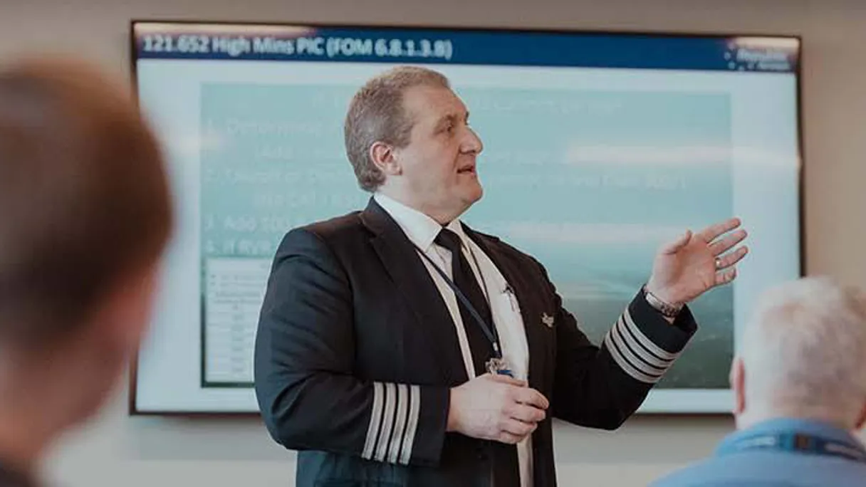 a person in a suit standing in front of a screen